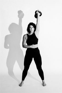 a woman is holding a kettle while posing for a black and white photo with her shadow on the wall