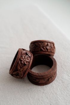 two wooden rings sitting on top of a white cloth covered table next to each other