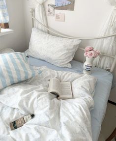 a white bed topped with pillows and a book