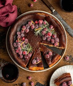 a chocolate tart with berries on top and slices cut from the side, sitting on a plate next to a glass of wine