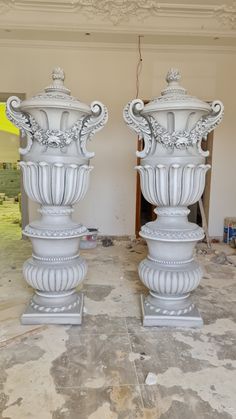 two large white vases sitting on top of each other