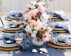 the table is set with plates, napkins and flowers in vases on it