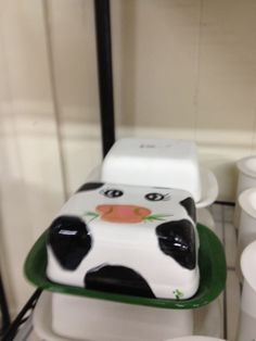 a cake shaped like a cow sitting on top of a green tray in the shape of a car