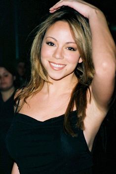 a beautiful young woman in a black dress posing for the camera with her hand on her head