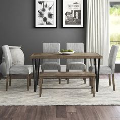 a dining room with gray walls and wooden flooring is pictured in this image, there are two framed pictures on the wall above the dinning table