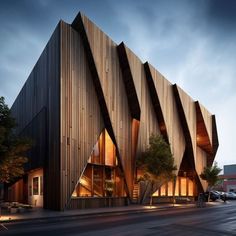 an architecturally designed building on the corner of a street at night with cars parked in front