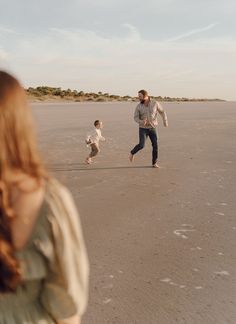 a man and two children are running on the beach with an adult in the background