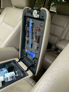 the inside of a car with tools and other items in its storage compartment on the back seat