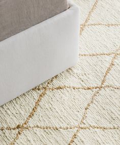 a close up view of a white rug on the floor with beige and brown accents