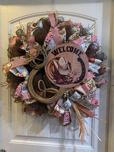 a welcome wreath is hanging on the front door with ribbon and ribbons attached to it