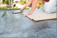 a man laying on top of a wooden floor next to another person with a tool