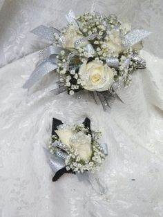 two bridal bouquets with white roses and baby's breath are on the bed