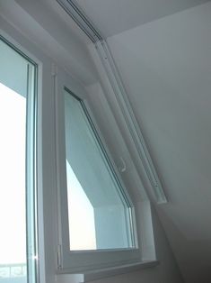 an open window in the corner of a room with white walls and windowsills