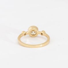 Inspired by Theia, the Greek Titan Goddess of Light, this three-stone ring by designer M.Hisae blends her signature circular motifs with dense, luscious gold. Each diamond is responsibly-sourced and conflict-free, making this unique ring as beautiful from within as it is to the eye. Wear it alone as a bold statement piece or with a curved band for a clever mix of curves and shapes. Made in the U.S.A. 14 karat gold set with a 0.76 ct center round white diamond, two 3 mm side stones, and eight 1 m Modern Three Stone Yellow Gold Jewelry, Modern Three Stone Round Jewelry, Yellow Gold Three Stone Cluster Ring, Yellow Gold Cluster Ring With Three Stones, Gold Three Stone Cluster Ring, Goddess Of Light, Greek Titans, Eye Wear, Unique Ring