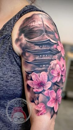 a woman's arm with pink flowers on it and a pagoda in the background