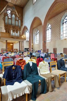 rows of tables and chairs with cloths on them in a large room filled with windows