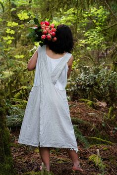 a woman in a white dress is walking through the woods with flowers on her head