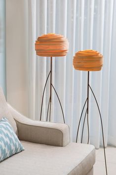 two floor lamps sitting on top of a white couch