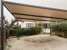 an outdoor covered patio area with gravel and trees