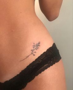 a woman's stomach with a small flower tattoo on her left side ribcage