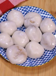 a blue and white plate filled with donuts on top of a wooden table next to a red checkered towel