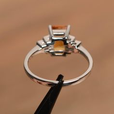 It is a natural citrine ring. The main stone is 6 mm*8 mm emerald cut.weight about 1.43 carats. The basic metal is sterling silver and plated with rhodium. To change the metal to a solid gold (white/rose) or platinum is also available, please ask for a quotation if you want. You can also go to my shop Home for more elegant rings: https://www.etsy.com/shop/godjewelry?ref=hdr_shop_menu More citrine rings: https://www.etsy.com/shop/godjewelry?ref=seller-platform-mcnav&search_query=citrine Custo Silver Solitaire Engagement Ring, Citrine Rings, Yellow Gemstone Ring, Citrine Ring Engagement, Elegant Rings, Black Spinel Ring, Engagement Ring Photos, Spinel Ring, Bezel Set Ring