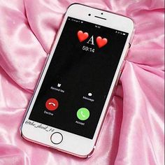 an iphone with hearts on the screen is laying on a pink satin surface and it appears to be sending messages