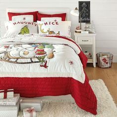 a bed with red and white comforters in a bedroom next to a christmas tree