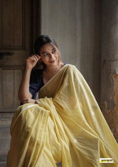 a woman in a yellow sari sitting on the ground with her hand on her head