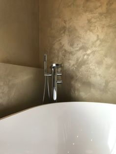 a large white bath tub sitting next to a wall mounted faucet in a bathroom