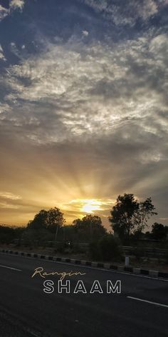 the sun is setting behind some clouds in the sky over an empty road with trees