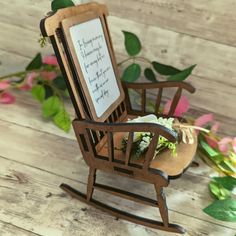 a miniature rocking chair with flowers and a sign on it