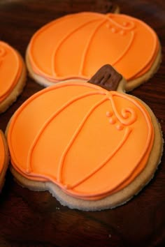 four decorated cookies with orange icing on a wooden table