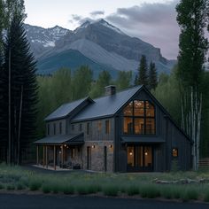 a large house sitting in the middle of a forest next to a tall mountain range