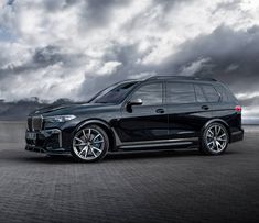 a black bmw suv parked in front of a cloudy sky