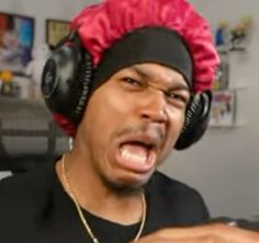 a man with headphones and a red wig on his head is making a face