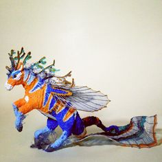 a blue and orange dragon figurine sitting on top of a white table next to a wall