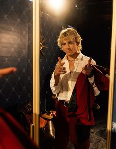 a man standing in front of a mirror pointing to his shirt on the hanger