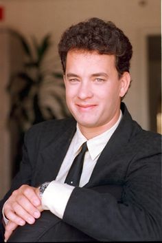 a man in a suit and tie posing for the camera with his arms crossed,