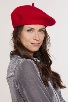 a woman wearing a red beret standing in front of a white background