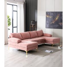 a living room with a pink sectional couch and rugs on the floor in front of a large window