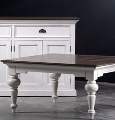 a white and brown table with drawers in the back ground next to a black wall