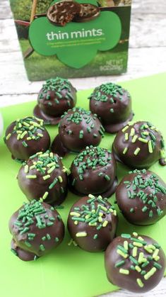 chocolate covered donuts with green sprinkles on a table next to a box of mints