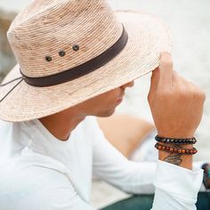 These men's bracelets by Lotus and Luna are wonderfully handcrafted by local female artisans in Thailand. They are made with semi-precious stones, 100% cotton cords and coconut shell clasps. Some of the stones used include Jade, Lava Stone, Turquoise and Hematite. The cords are fully adjustable to four different size options, so that you may get the perfect fit. Length ranges from 7.85 in at the first closure to 10.25 in at the last closure, so it will fit most wrists. Simply adjust to your perf Hand-strung Brown Wrap Bracelet For The Beach, Adjustable Brown Artisan Braided Bracelet, Adjustable Artisan Brown Braided Bracelets, Brown Bracelet As Summer Gift, Brown Bracelets, Summer Gift, Brown Bracelets As Summer Gifts, Brown Summer Bracelets As Gift, Brown Summer Bracelets As Gifts, Brown Natural Stone Beaded Bracelets For Beach