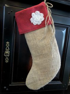 a burlocked stocking hanging on the front door is adorned with a white flower