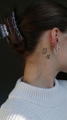 a woman with a small butterfly tattoo on her left side of her neck and behind her ear