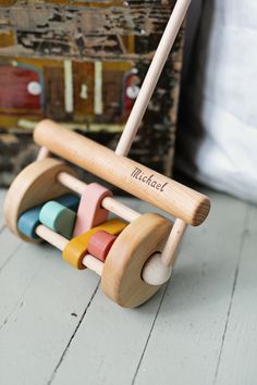 a wooden rocking toy with personalized name on it and colorful blocks in front of a suitcase