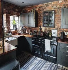 a kitchen with an oven, sink and counter tops in black painted wooden cabinets next to a brick wall