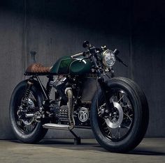 a black motorcycle parked in front of a gray wall with the lights on it's side