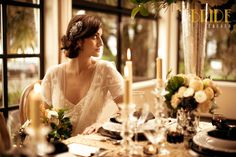 a woman sitting at a table with flowers and candles